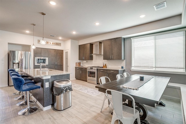 1112 Goldenrod Dr, Godley, TX 76044 - kitchen featuring appliances with stainless steel finishes, wall chimney exhaust hood, dark brown cabinets, a sink, and backsplash