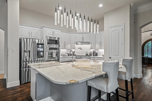 6500 Lazy Oak Ln, Plano, TX 75024 - kitchen with stainless steel appliances, arched walkways, a sink, dark wood finished floors, and a towering ceiling