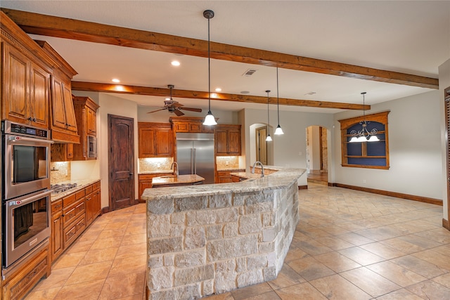 2454 Savanna Cir, Midlothian, TX 76065 - kitchen with built in appliances, arched walkways, a large island with sink, brown cabinetry, and beam ceiling