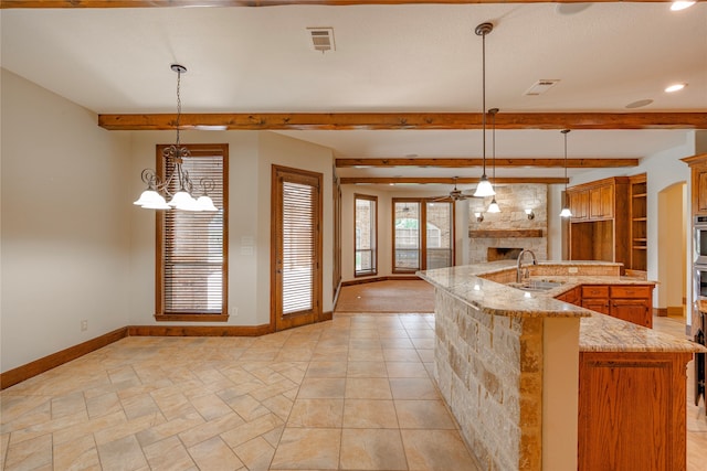 2454 Savanna Cir, Midlothian, TX 76065 - kitchen with a sink, a stone fireplace, baseboards, a chandelier, and beam ceiling