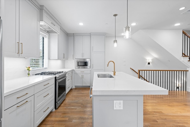4133 Emerson Ave Unit 1, University Park, TX 75205 - kitchen featuring appliances with stainless steel finishes, a sink, light wood-style flooring, backsplash, and an island with sink
