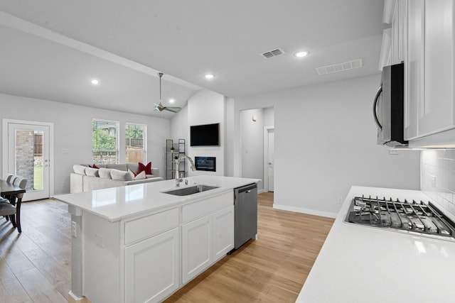 10650 Barrington Ln, Fort Worth, TX 76126 - kitchen with stainless steel appliances, a glass covered fireplace, light wood-style flooring, white cabinetry, and a center island with sink
