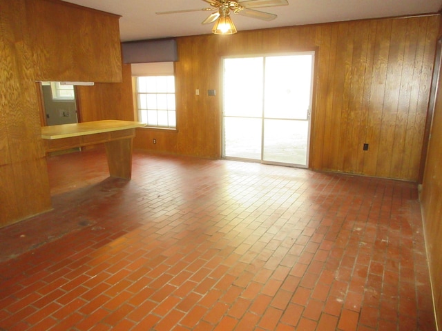 611 W 4th St, Homer, LA 71040 - unfurnished living room with ceiling fan, wood walls, and brick floors