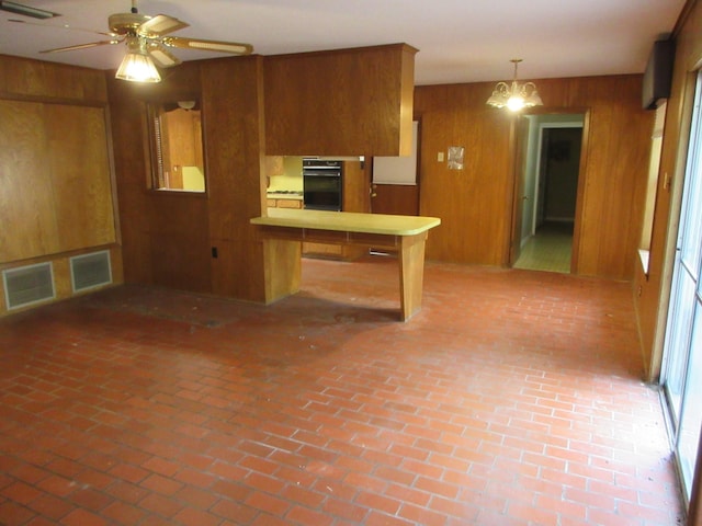 611 W 4th St, Homer, LA 71040 - kitchen with wood walls, oven, a peninsula, brown cabinetry, and light countertops