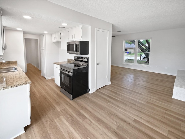 7620 Clover Ln, Watauga, TX 76148 - kitchen featuring appliances with stainless steel finishes, a textured ceiling, a sink, light wood-style flooring, and white cabinets
