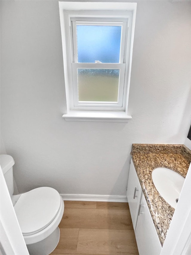 7620 Clover Ln, Watauga, TX 76148 - half bathroom with vanity, wood finished floors, toilet, and baseboards