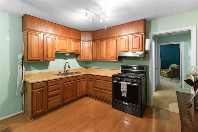 2311 Anderson St, Irving, TX 75062 - kitchen featuring range with gas stovetop, under cabinet range hood, a sink, light countertops, and light wood-style flooring