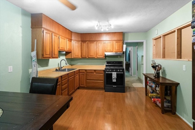 2311 Anderson St, Irving, TX 75062 - kitchen with range with gas stovetop, a sink, under cabinet range hood, light countertops, and light wood-type flooring