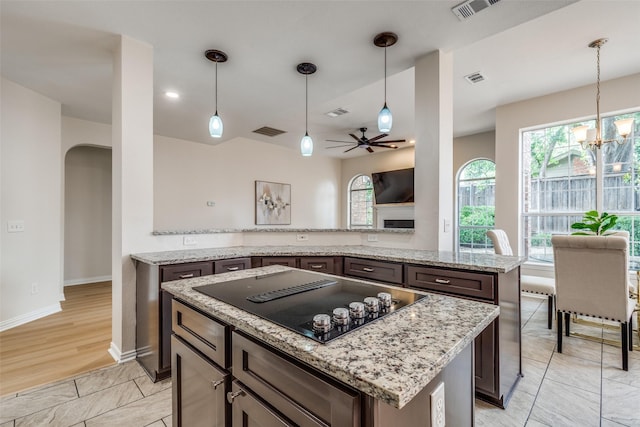 4037 Azure Ln, Addison, TX 75001 - kitchen featuring black electric stovetop, arched walkways, a kitchen island, a chandelier, and plenty of natural light