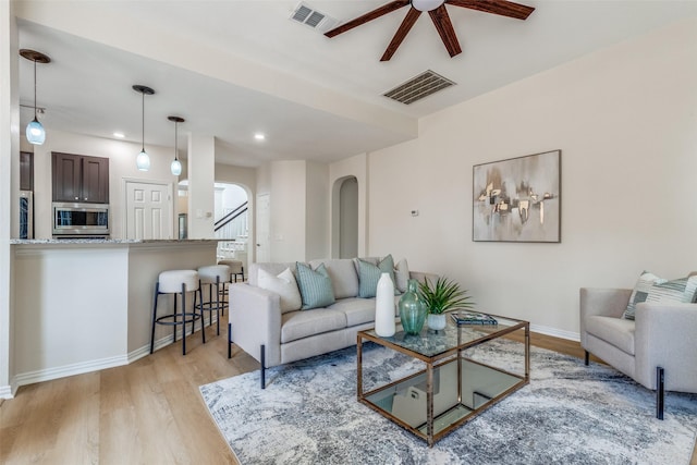 4037 Azure Ln, Addison, TX 75001 - living room with arched walkways, a ceiling fan, light wood finished floors, baseboards, and stairs
