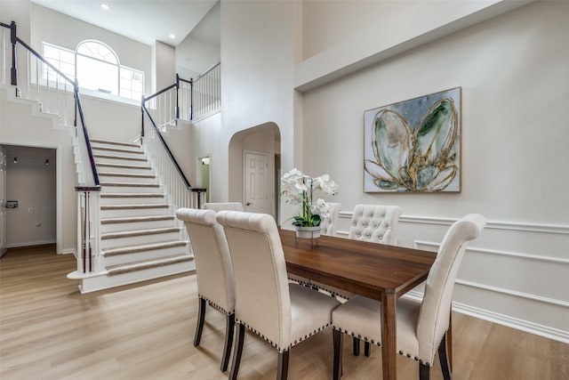 4037 Azure Ln, Addison, TX 75001 - dining space featuring stairs, light wood-style flooring, a towering ceiling, arched walkways, and recessed lighting