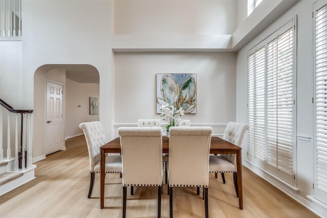 4037 Azure Ln, Addison, TX 75001 - dining room with arched walkways, a high ceiling, stairs, light wood finished floors, and plenty of natural light