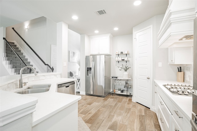 1507 Calcot Ln, Forney, TX 75126 - kitchen featuring appliances with stainless steel finishes, a sink, custom range hood, light wood-style flooring, and white cabinets