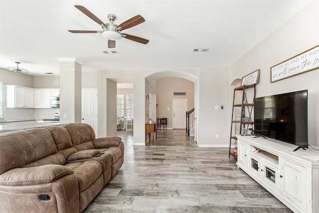 1253 Stone Ln, Celina, TX 75009 - living room featuring ceiling fan, arched walkways, light wood-type flooring, and baseboards