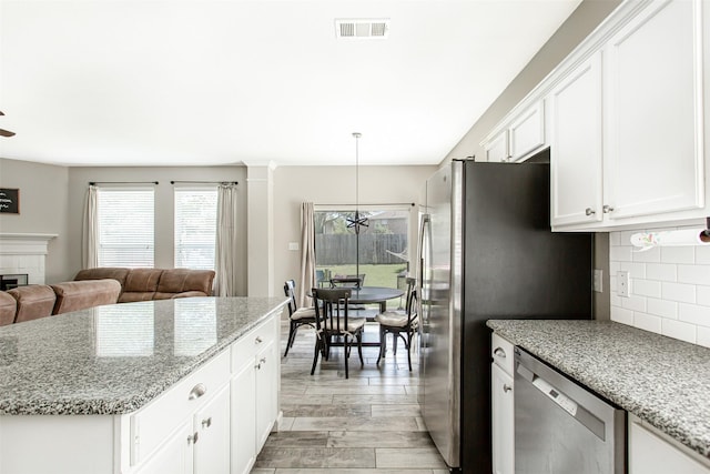 1253 Stone Ln, Celina, TX 75009 - kitchen with stainless steel appliances, open floor plan, decorative backsplash, white cabinetry, and light stone countertops