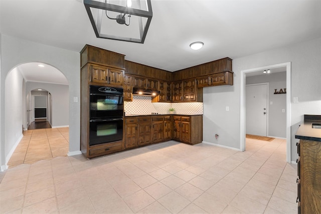 7624 Lake Highlands Dr, Fort Worth, TX 76179 - kitchen featuring under cabinet range hood, light tile patterned floors, tasteful backsplash, arched walkways, and baseboards