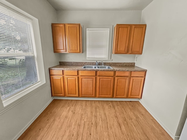 109 S 5th St, Sanger, TX 76266 - kitchen with a sink, light wood-style floors, brown cabinets, and dark countertops
