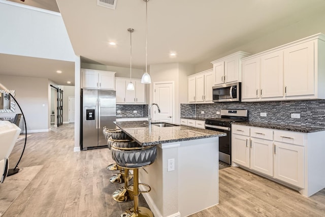 1225 Elmwood Dr, Cedar Hill, TX 75104 - kitchen featuring appliances with stainless steel finishes, a sink, a kitchen breakfast bar, an island with sink, and light wood-style floors
