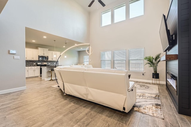 1225 Elmwood Dr, Cedar Hill, TX 75104 - living room with a ceiling fan, light wood-type flooring, a fireplace, a high ceiling, and baseboards