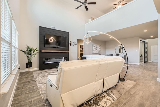 1225 Elmwood Dr, Cedar Hill, TX 75104 - living area featuring light wood-style floors, a high ceiling, a ceiling fan, baseboards, and a barn door