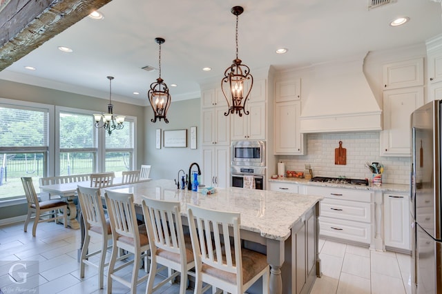 1029 Spanish Moss Cir, Bossier City, LA 71111 - kitchen featuring appliances with stainless steel finishes, premium range hood, a chandelier, tasteful backsplash, and light stone counters