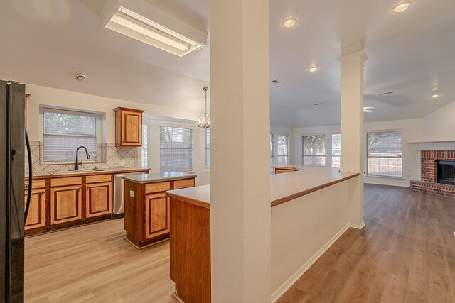 7028 Herman Jared Dr, North Richland Hills, TX 76182 - kitchen with freestanding refrigerator, brown cabinets, light wood-style floors, a sink, and decorative backsplash
