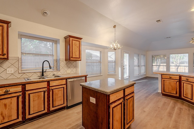 7028 Herman Jared Dr, North Richland Hills, TX 76182 - kitchen featuring stainless steel dishwasher, a sink, brown cabinetry, light wood-style flooring, and decorative backsplash