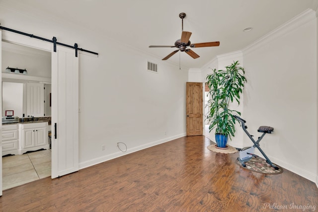 129 Carondelet Ct, Bossier City, LA 71111 - spare room featuring ceiling fan, ornamental molding, a barn door, baseboards, and wood finished floors