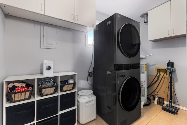417 Birchwood Cir, Mesquite, TX 75149 - laundry room featuring estacked washer and dryer, light tile patterned floors, cabinet space, and water heater