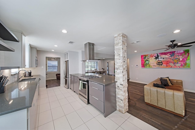 3116 Sharpview Ln, Dallas, TX 75228 - kitchen with appliances with stainless steel finishes, decorative columns, island exhaust hood, light wood finished floors, and ceiling fan