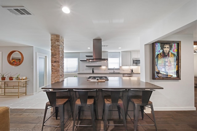 3116 Sharpview Ln, Dallas, TX 75228 - kitchen featuring island range hood, stainless steel appliances, white cabinets, a breakfast bar area, and dark countertops