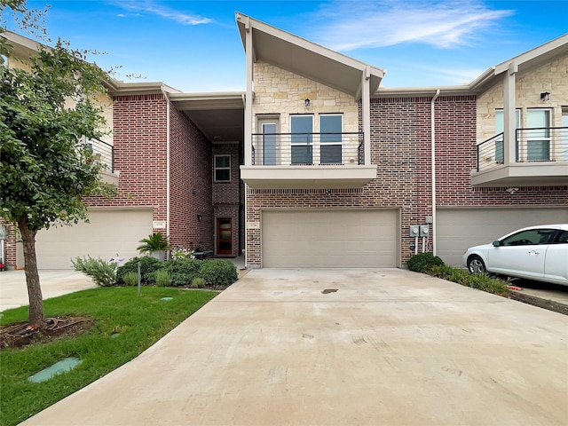 5704 Woodlands Dr, The Colony, TX 75056 - townhome / multi-family property with a garage, driveway, brick siding, stone siding, and a balcony