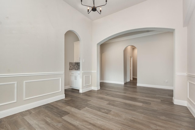 302 Micco Ln, Rockwall, TX 75087 - empty room with arched walkways, wood finished floors, a chandelier, vaulted ceiling, and baseboards