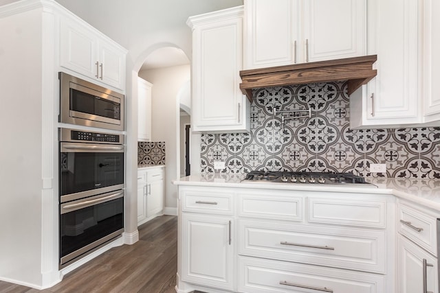 302 Micco Ln, Rockwall, TX 75087 - kitchen with appliances with stainless steel finishes, backsplash, white cabinetry, arched walkways, and light countertops