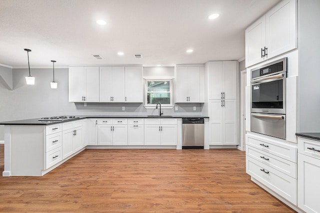 6412 Regal Rd, Forest Hill, TX 76119 - kitchen featuring appliances with stainless steel finishes, a warming drawer, a peninsula, dark countertops, and white cabinetry