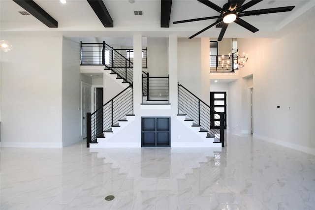 10787 Leake Ln, Frisco, TX 75035 - staircase featuring a towering ceiling, beam ceiling, a chandelier, ceiling fan, and baseboards