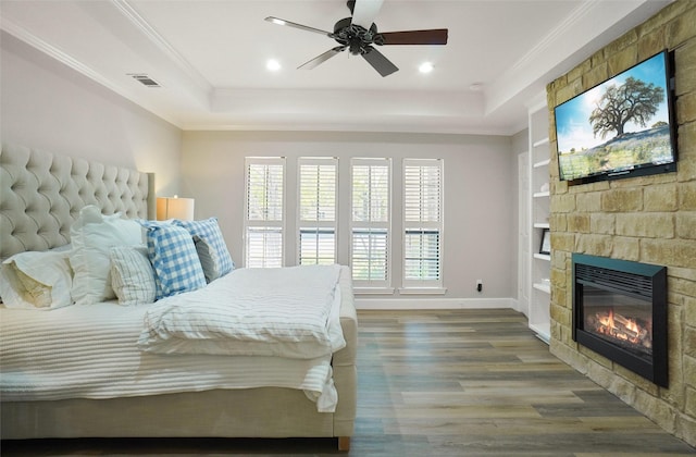 7208 Maranatha Ct, Colleyville, TX 76034 - bedroom featuring a tray ceiling, wood finished floors, a stone fireplace, ornamental molding, and baseboards