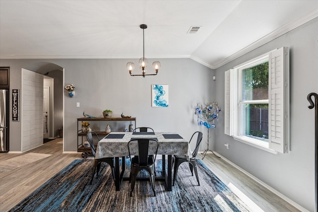 901 Freesia Dr, Little Elm, TX 75068 - dining room featuring wood finished floors, crown molding, arched walkways, a chandelier, and vaulted ceiling