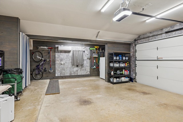 901 Freesia Dr, Little Elm, TX 75068 - garage featuring a garage door opener, freestanding refrigerator, and a wall mounted air conditioner