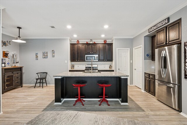901 Freesia Dr, Little Elm, TX 75068 - kitchen featuring stainless steel appliances, decorative backsplash, light wood finished floors, ornamental molding, and dark brown cabinets