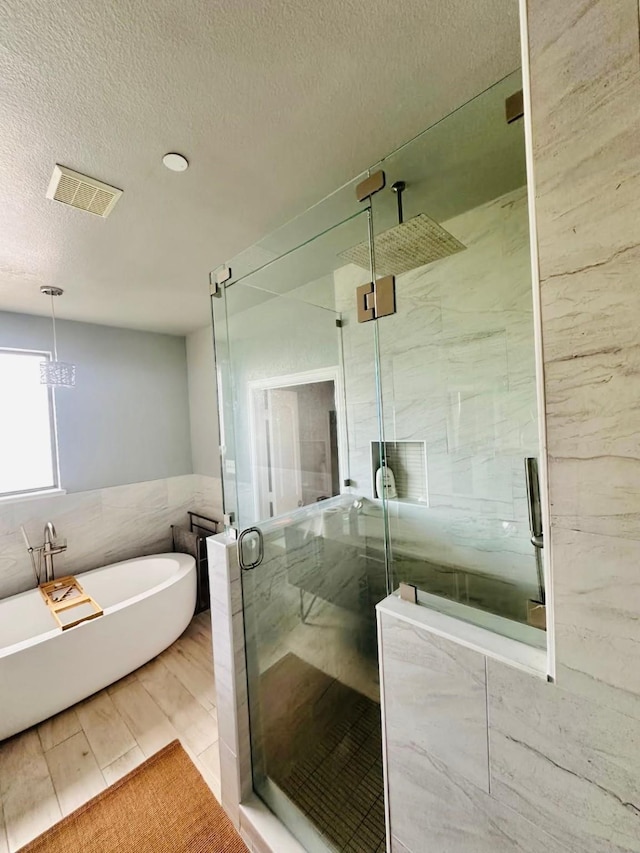 5701 Pantheon Ct, Plano, TX 75024 - full bathroom featuring tile walls, a marble finish shower, a freestanding bath, and a textured ceiling