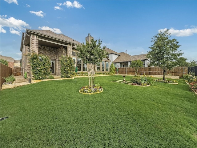 1316 Heather Ln, Little Elm, TX 75068 - back of house featuring a fenced backyard, brick siding, and a chimney