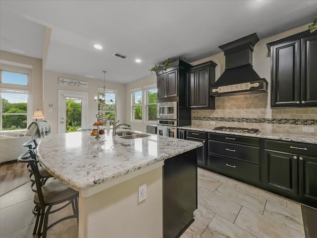 1316 Heather Ln, Little Elm, TX 75068 - kitchen with premium range hood, stainless steel appliances, dark cabinets, light stone counters, and backsplash