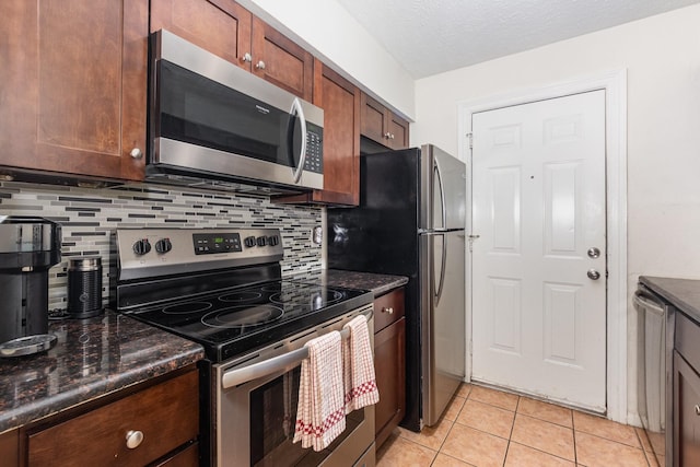 4317 Hartford St Unit 102, Dallas, TX 75219 - kitchen featuring appliances with stainless steel finishes, decorative backsplash, light tile patterned floors, and dark stone counters