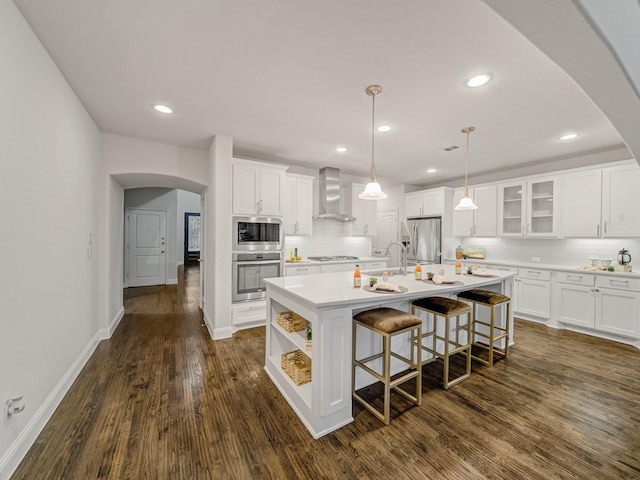 413 Winehart St, Lewisville, TX 75056 - kitchen with wall chimney exhaust hood, stainless steel appliances, arched walkways, dark wood-style flooring, and white cabinetry