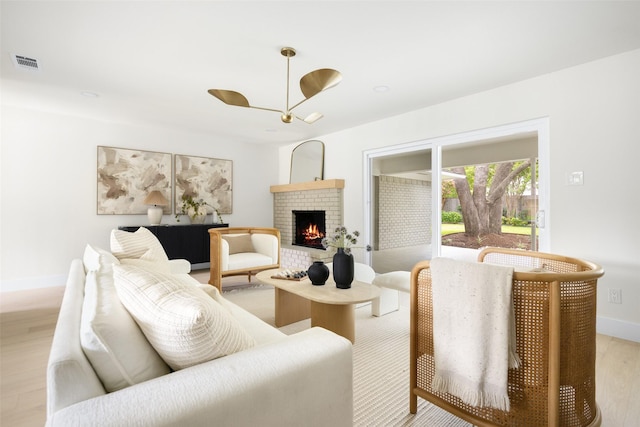 7716 Roundrock Rd, Dallas, TX 75248 - living room featuring light wood-style floors, a fireplace, and a chandelier