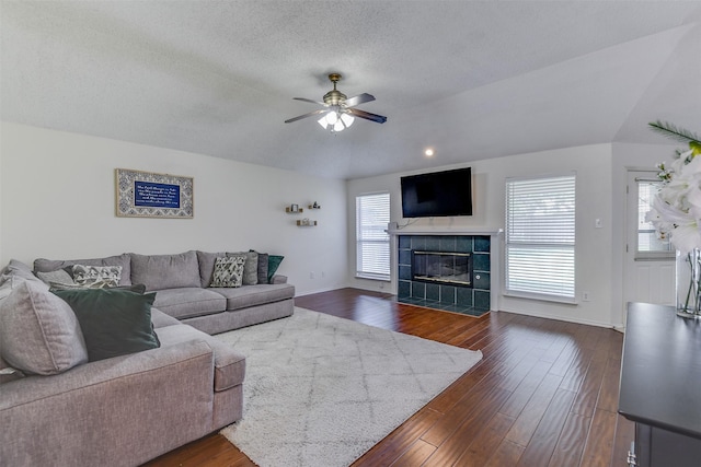 4546 Brittany Ln, Grand Prairie, TX 75052 - living room featuring a ceiling fan, a tiled fireplace, dark wood-type flooring, baseboards, and a textured ceiling