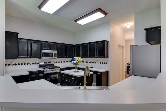 4546 Brittany Ln, Grand Prairie, TX 75052 - kitchen featuring stainless steel appliances, a sink, backsplash, dark cabinets, and light countertops