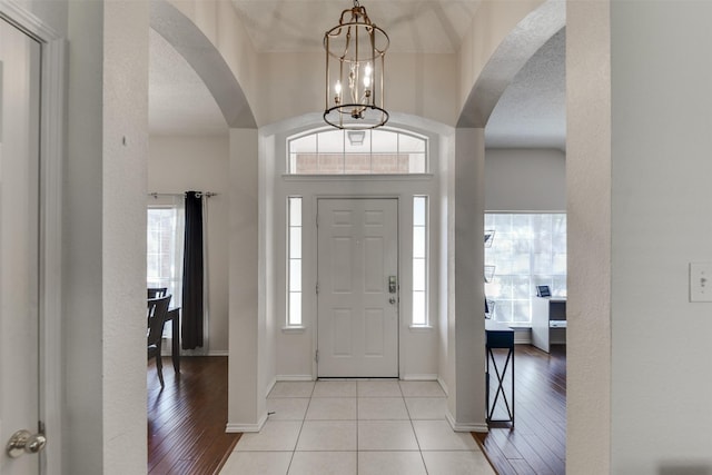 4546 Brittany Ln, Grand Prairie, TX 75052 - foyer entrance featuring arched walkways, a chandelier, light tile patterned floors, and baseboards