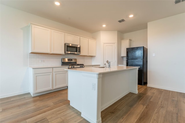 3616 Mallard Way, Mckinney, TX 75071 - kitchen featuring appliances with stainless steel finishes, a sink, light wood-style floors, backsplash, and an island with sink